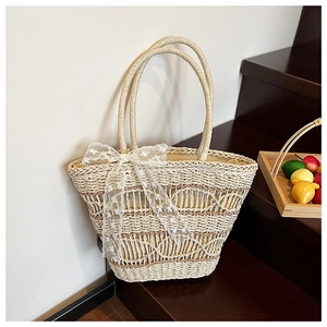 Close-up of woven straw tote bag with brown stripe detail and white lace bow