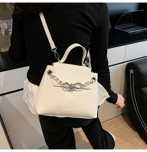 Detailed view of white faux leather crossbody bag with silver woven chain knot buckle