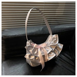 Detail of silver satin half-moon bag with pink silk bow and ruffled lace accents
