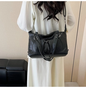 Detail of a black large-capacity tote bag with drawstring and silver hardware accents