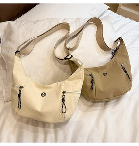 Détail des sacs à bandoulière en forme de croissant crème et kaki sur une literie douce