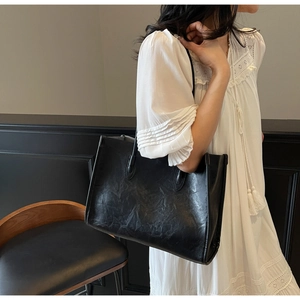 Close-up of black tote bag featuring vintage wrinkled texture and minimalist handles