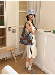 Brown nylon crescent bag with blue floral print worn by a model in a casual indoor setting