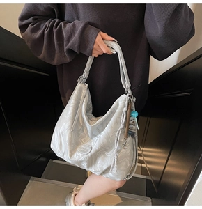 Close-up of metallic silver hobo bag with liquid metal texture and blue bead charm