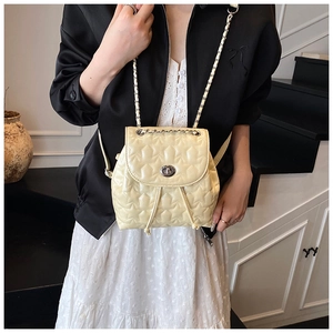 Detail of cream quilted mini backpack with star pattern and chain strap on a model