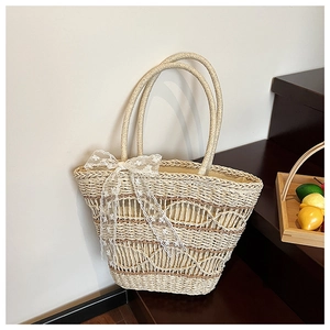 Detail of woven straw tote bag with wave texture and decorative white lace bow