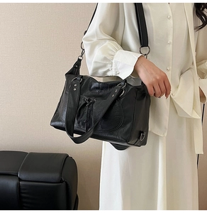 Detail of black motorcycle shoulder bag with silver studs and crinkled leather texture