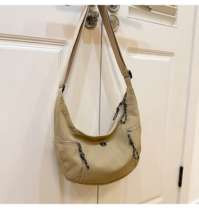 Détail du sac demi-lune en nylon kaki avec poches zippées et tirettes tissées