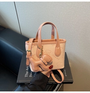 Gros plan détaillé du mini sac cabas rose en cuir avec relief chien et breloque mignonne