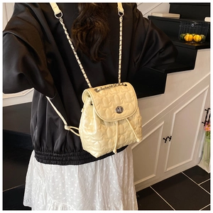 Detail of cream quilted backpack with star pattern and chain straps on model
