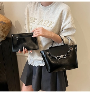 Detail of black faux leather tote bag with silver bow chain and matching pouch set