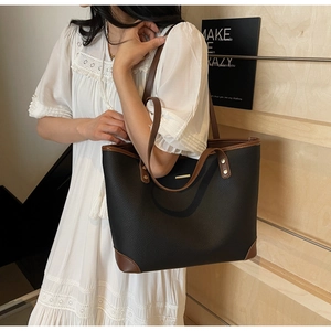 Dettaglio della borsa tote in pelle litchi opaca con finiture marroni e logo in metallo