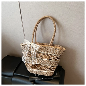 Detailed weave pattern of a handmade straw tote bag with a white lace bow accent