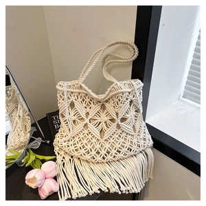 Detailed close-up of handmade beige macramé tote bag with geometric patterns and long tassels