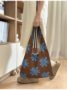 Detail of a brown nylon hobo bag with blue floral prints in a cozy home interior setting