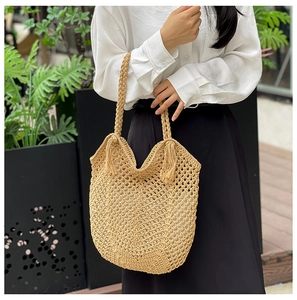 Détail du sac de plage tressé avec pompon décoratif et poignée ergonomique tissée