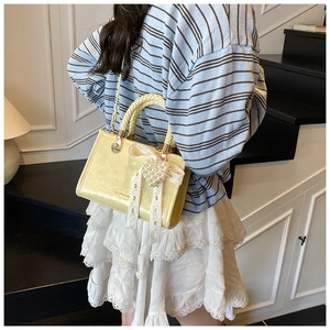 Close-up of yellow crossbody bag featuring woven handles and a pearl heart lace bow