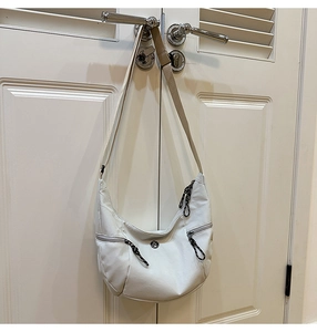 Détail du sac blanc avec deux poches à fermeture éclair frontales et tirettes tissées