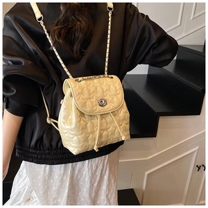 Detail of cream star-quilted backpack with silver chain strap and drawstring closure