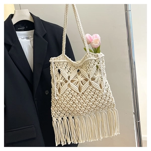 Macro detail of beige macrame tote bag featuring geometric knit patterns and long tassels