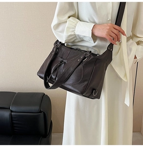 Close-up of a large coffee brown leather tote bag with rivets and drawstring detail