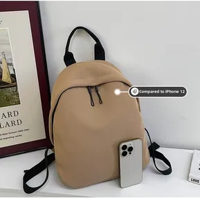 Mini khaki oxford backpack compared with iPhone 12 showing its compact travel size
