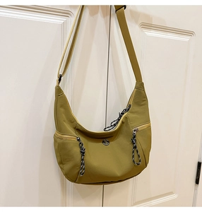 Détail du sac dumpling vert avec logo en métal, fermeture éclair et sangle réglable