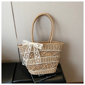 Detail of woven straw tote bag with lace bow decoration and hollow wave patterns