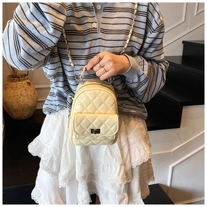 Detail of a mini quilted backpack in beige patent leather with metal chain straps