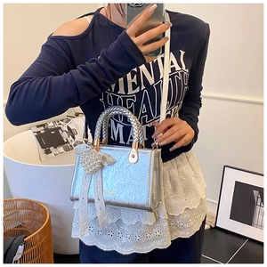 Silver metallic crossbody bag with chunky woven handle and pearl bow charm detail