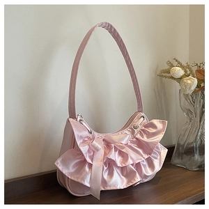 Close-up of a pink shoulder bag with satin ruffles, silk bows and a crescent shape