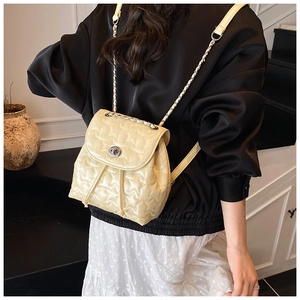 Detail of star-quilted cream backpack with gold chain strap and drawstring closure