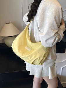 Yellow half-moon nylon crossbody bag with pleated texture and wide strap for daily commute
