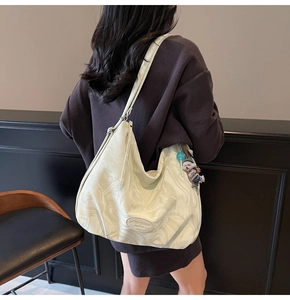 Detailed view of large off-white tote bag with marble pattern and cute pendant on model