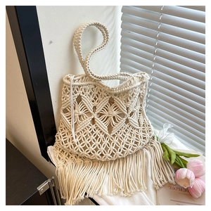 Detail of bohemian cream woven tote bag with fringe tassels and intricate cotton texture
