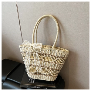 Close-up of handwoven straw tote bag featuring white lace bow and ripple pattern texture
