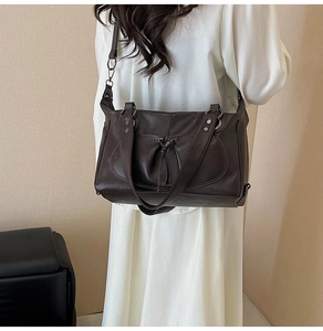 Detail of dark brown faux leather tote bag with drawstring pocket and metal studs
