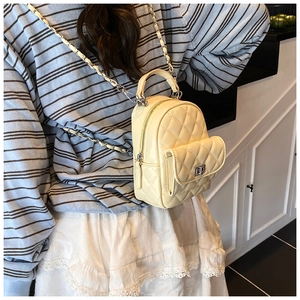 Quilted mini backpack in light yellow with chain strap shown on person in a home setting