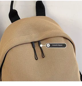Close-up of khaki mesh backpack featuring smooth black double zippers and top webbing handle