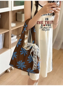 Detail of floral nylon crescent bag with a decorative cream lace bow and printed pattern