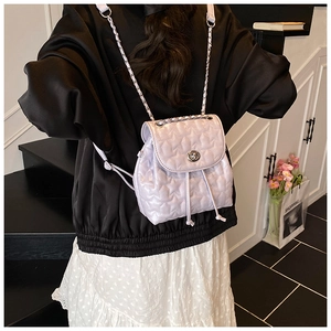 Rear view of a model wearing the small lavender star-quilted backpack with silver chains