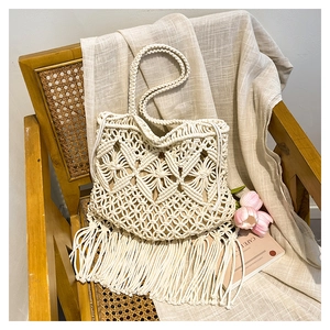 Close-up of handmade cream macrame tote bag with intricate diamond weave and long fringe