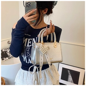 Detail of silver pleated handbag with heart pearl charm and lace bow decoration