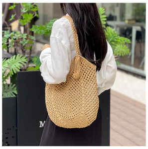 Gros plan du sac en paille tissé kaki avec détail de pompon et texture ajourée