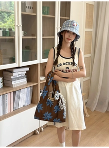 Detail of floral tote bag with lace handles paired with a printed sleeveless dress