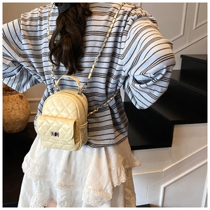 Detail of quilted diamond pattern and woven chain strap on cream mini backpack