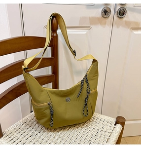 Détail du sac croissant en nylon jaune moutarde avec tirettes en corde sur chaise blanche