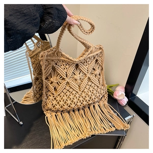Detail of woven straw tote bag featuring bohemian tassels and intricate diamond patterns