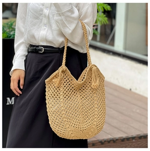 Détail du sac fourre-tout en maille tissée beige avec glands et poignée circulaire