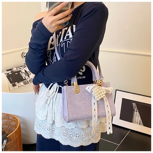 Close-up of lilac crossbody bag with lace bow and heart-shaped pearl charm detail